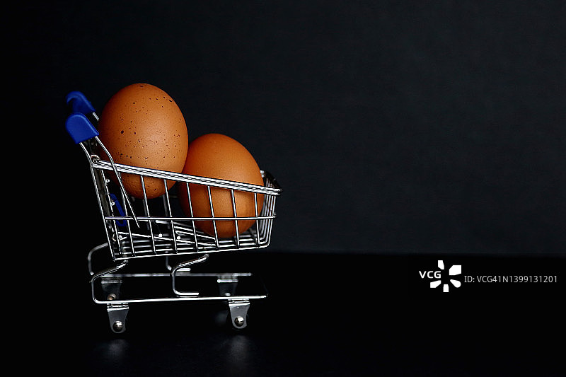 黑色背景下购物车里的农场鸡蛋图片素材