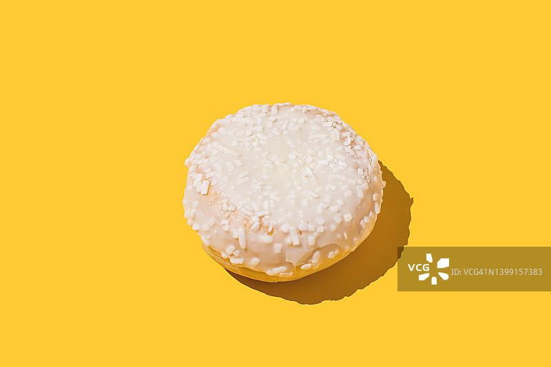 黄色背景上填充奶油的白色巧克力柏林甜甜圈，关于糖果、饼干、肥胖、糖和饮食的概念图片素材