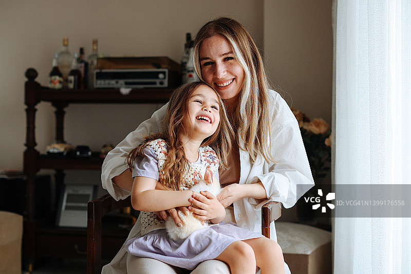 年轻的母亲和抱着白色兔子的可爱小女孩图片素材