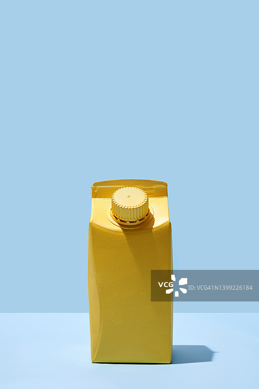 蓝色背景上的黄色小牛奶或果汁盒图片素材