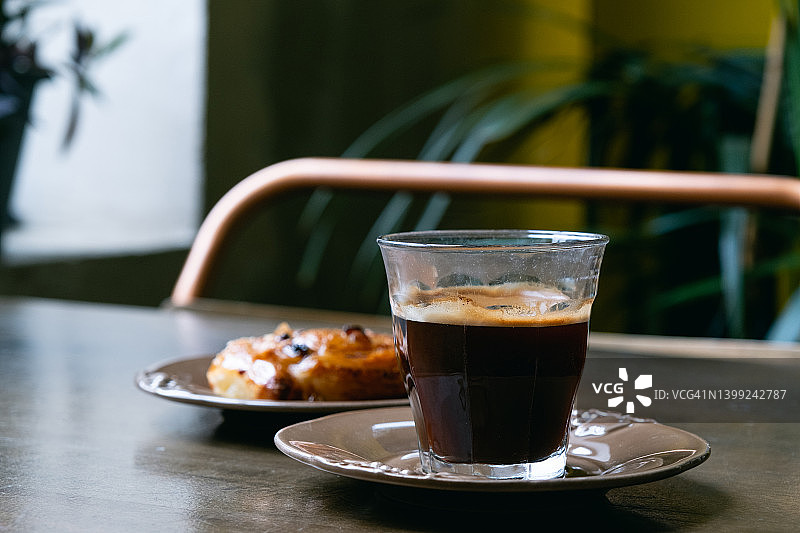 咖啡馆餐桌上的黑咖啡、羊角面包和葡萄干面包图片素材