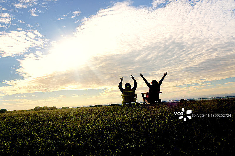两个女人坐在户外椅子上欣赏日落图片素材