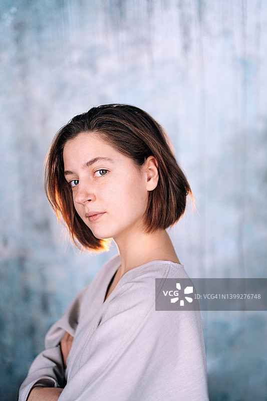 在蓝色墙壁背景下闭着眼睛的短发美丽年轻微笑女人。特写肖像。自然美概念图片素材