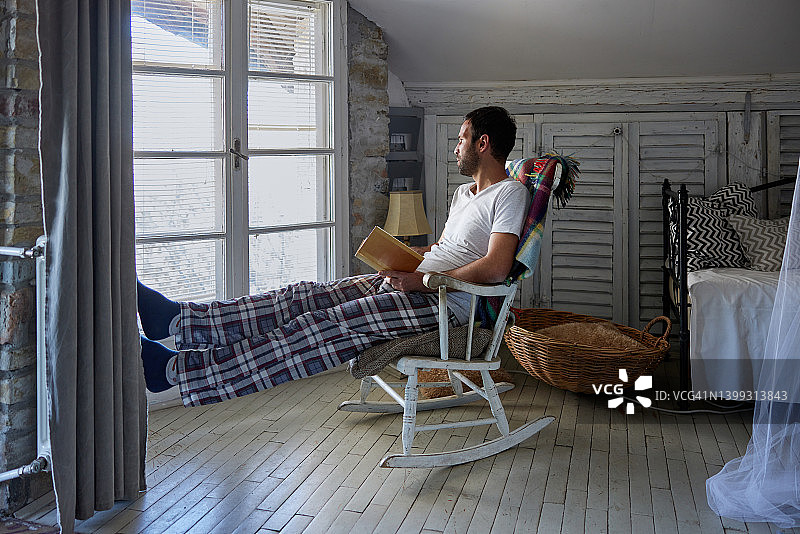 年轻男人在摇椅上看书放松图片素材