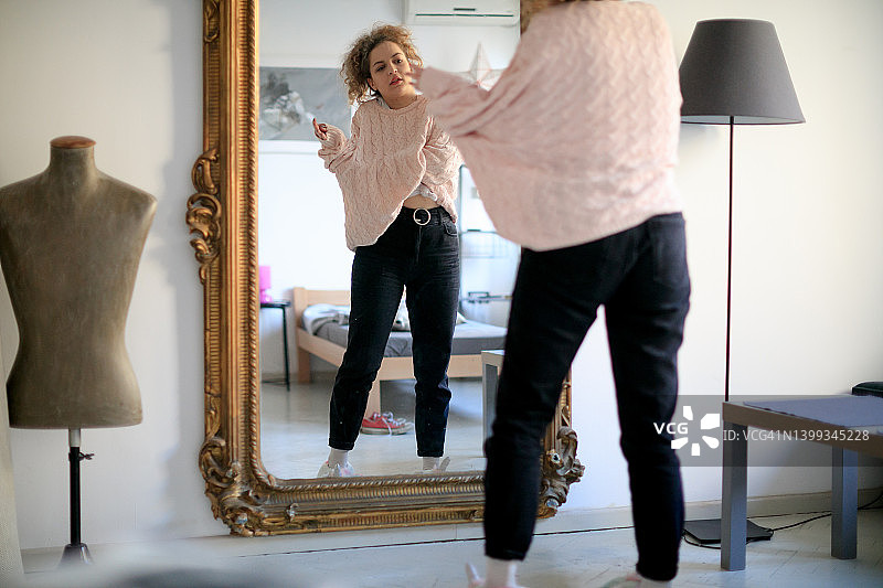 年轻女人在家中古典镜子前脱下毛衣图片素材