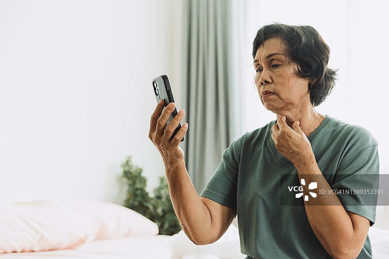 高级妇女谈在手机上视频电话医生在卧室。图片素材