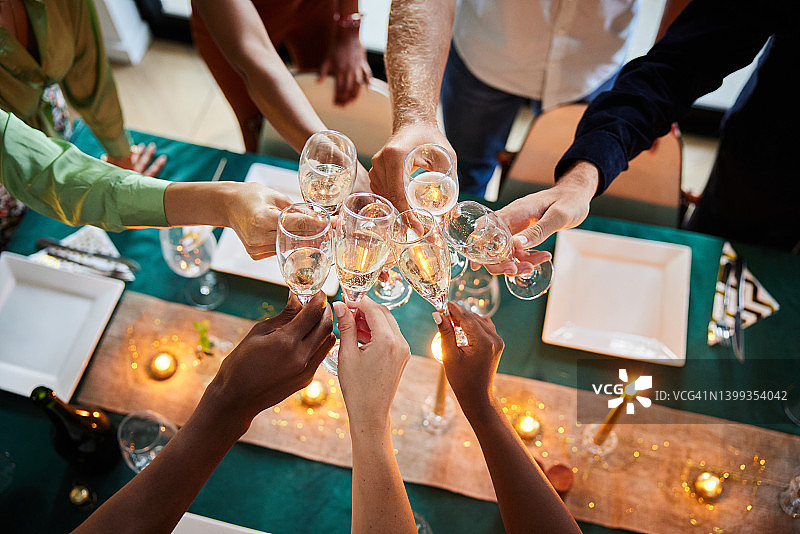 不同肤色的朋友在餐桌旁举杯庆祝晚餐聚会图片素材