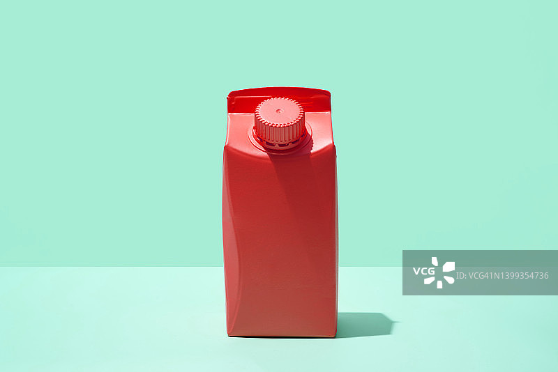 绿色背景上的红色小牛奶或果汁盒图片素材