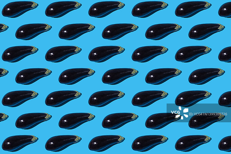 蓝色背景上带硬阴影的生茄子图案：蔬菜、健康食品概念图片素材