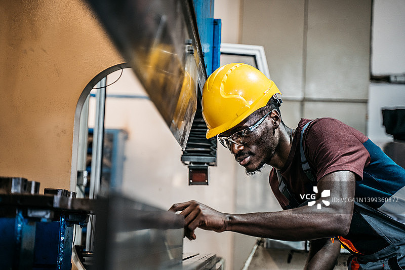 在工厂使用机器的非洲裔美国工人图片素材