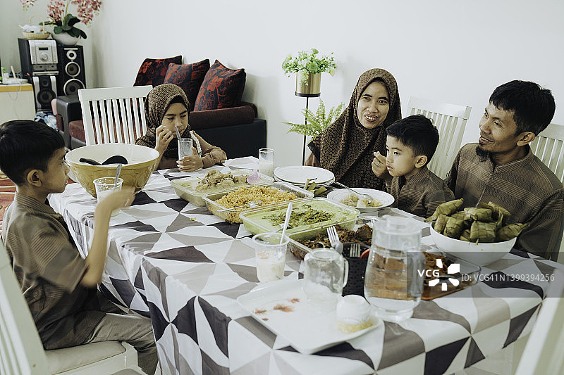 亚洲家庭庆祝开斋节，在家一起祈祷用餐图片素材