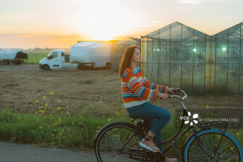 在温室附近骑自行车的女人图片素材