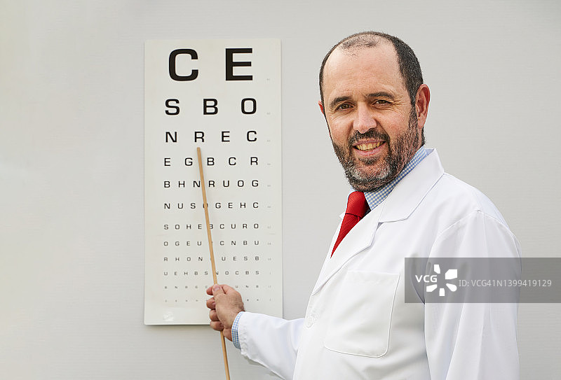 眼科医生穿着实验服，使用视力表检测。医疗保健概念。图片素材