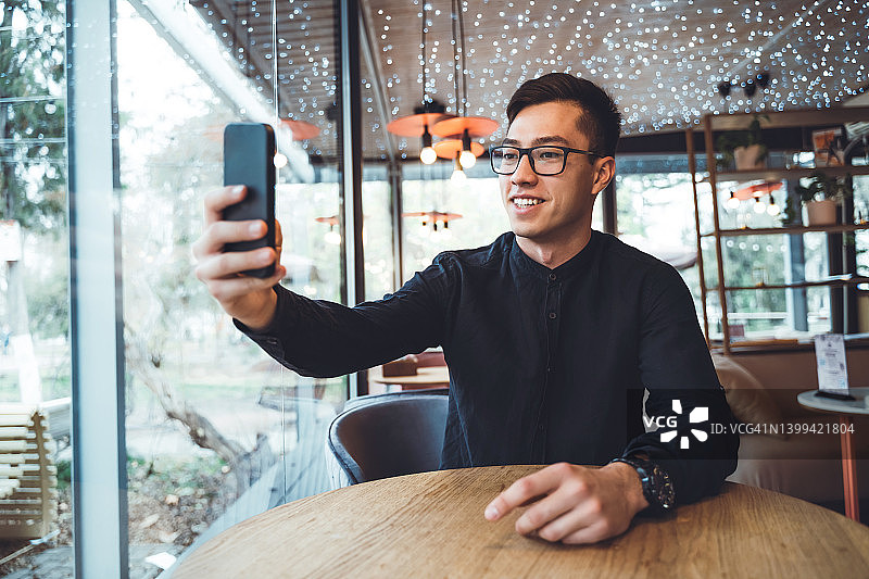 正在进行视频通话或用手机自拍的年轻亚洲男人图片素材