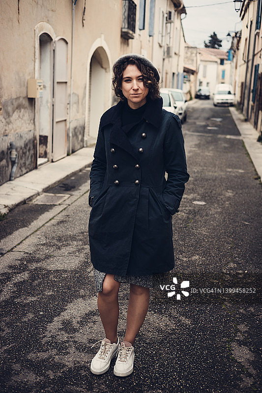 穿着蓝色风衣和白色运动鞋的女人在雨天参观阿维尼翁图片素材