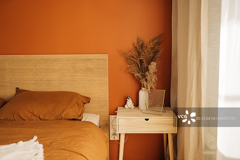 特写：卧室舒适床边，深蓝色墙壁旁摆放着白色床头柜和装饰品图片素材