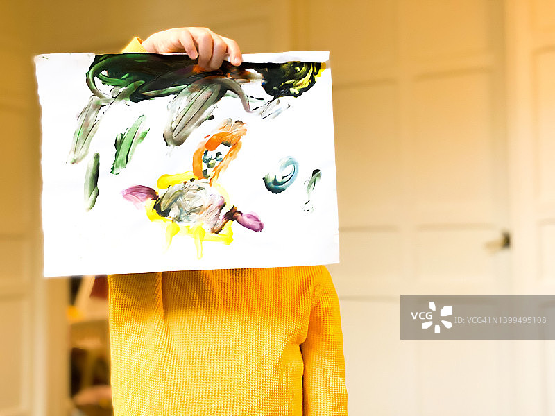 年轻的混血女孩在家举起画作挡住脸图片素材