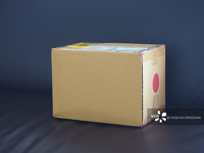 棕色纸盒在深棕色沙发背景上图片素材