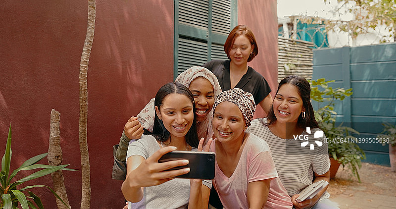 年轻女性在咖啡馆读书会自拍。女性朋友或学习小组用手机拍照图片素材