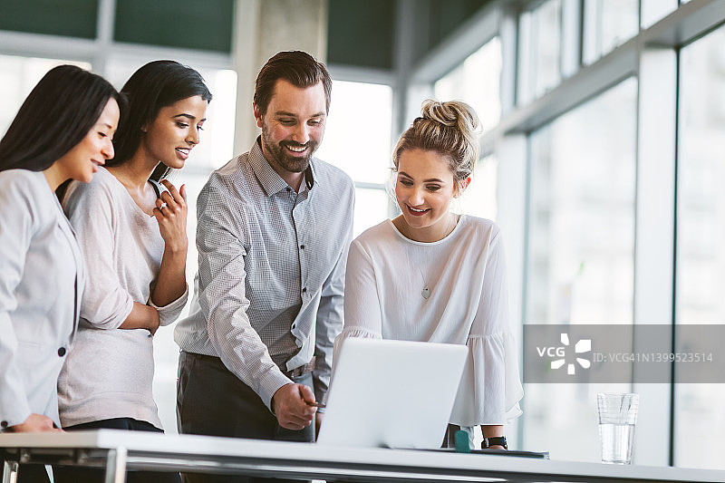 一群同事在明亮现代的商务办公室里一起使用笔记本电脑图片素材