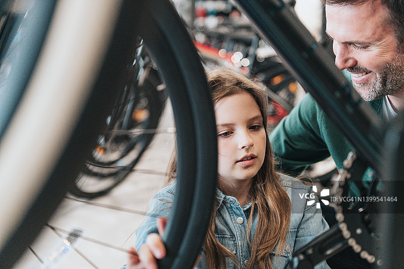 男人在自行车店向小女孩展示新自行车图片素材