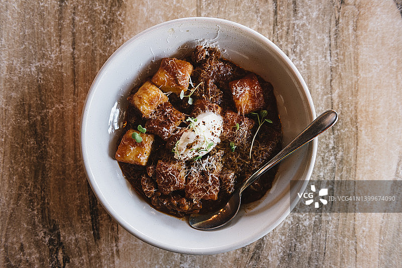 美味意式面疙瘩配慢炖牛肉酱，摆放在木质餐桌上图片素材