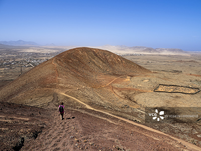 徒步者背着背包走在富埃特文图拉岛的火山景观中图片素材