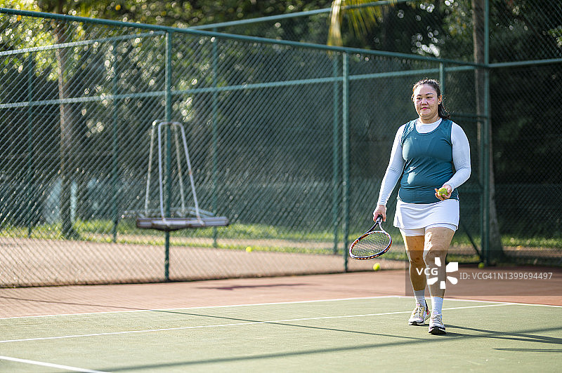 中国中年女子在网球场发球图片素材