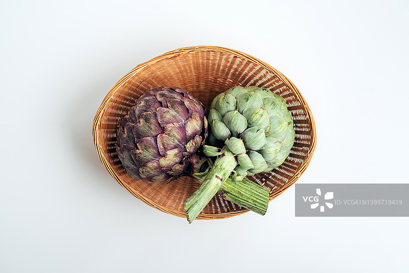柳条筐里的绿色和紫色朝鲜蓟。异国情调的蔬菜。健康食品。农场收获。菜肴配料。图片素材