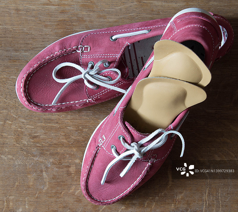 粉色运动鞋和带矫形鞋垫的粉色运动鞋，木质背景图片素材