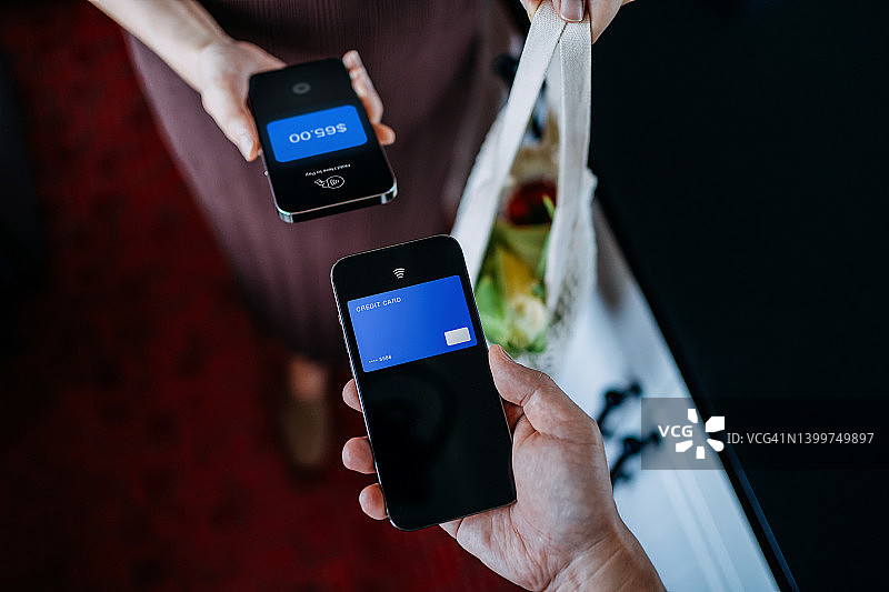 顾客和店主用手机进行支付，购买杂货，非接触式支付图片素材