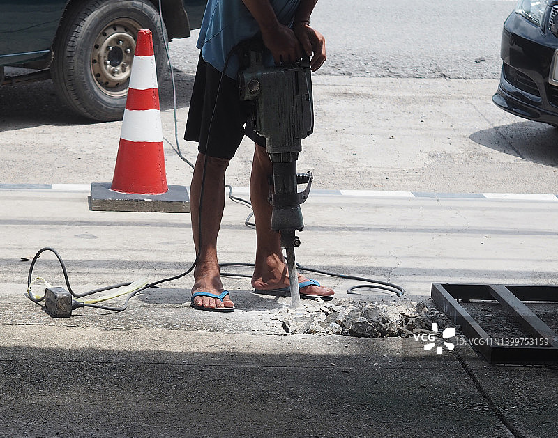 男人使用电动工具在水泥地板上钻孔图片素材
