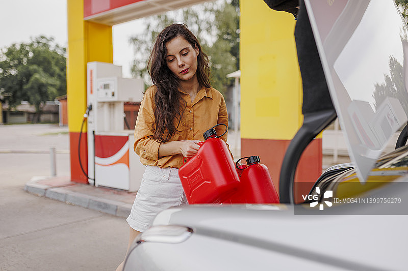在加油站拿着汽油罐的焦虑女人图片素材