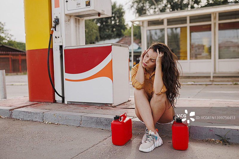 在加油站拿着汽油罐的沮丧的女人图片素材