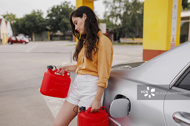 在加油站拿着汽油桶的沮丧女人图片素材