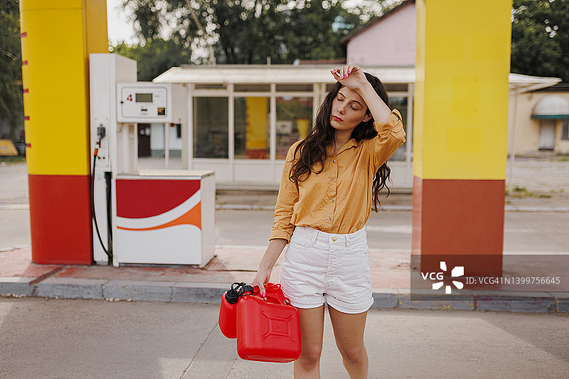 在加油站拿着汽油罐的沮丧的女人图片素材
