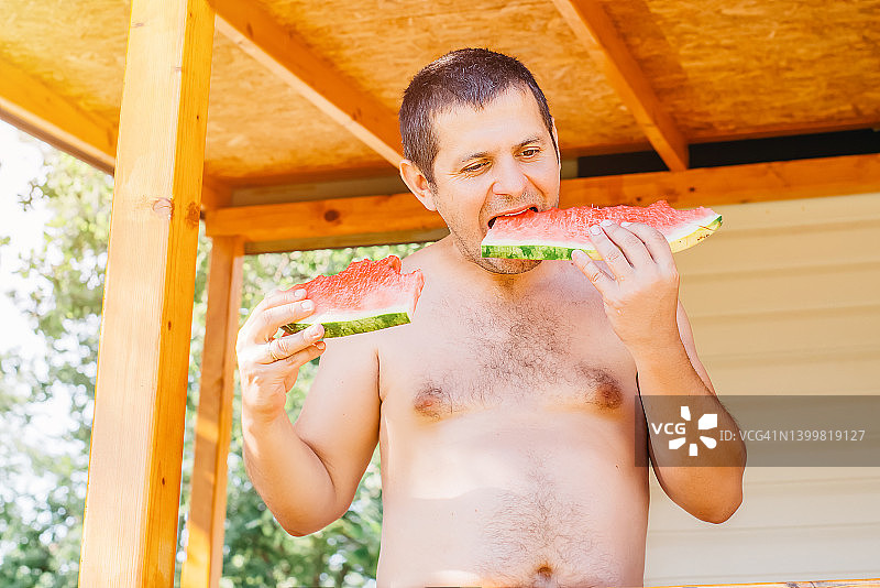 在夏日露台上吃西瓜的男人图片素材