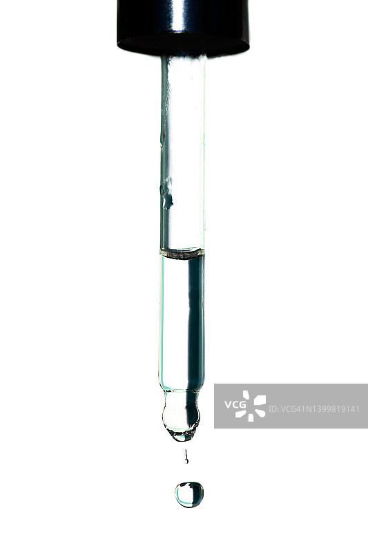 面部精华滴从玻璃滴管滴到白色背景上。美容程序和身体护理的概念。聚谷氨酸是一种新型透明质酸。宏观摄影图片素材