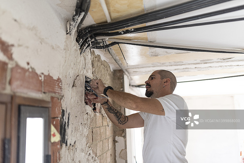 电工通过天花板和墙壁安装电力和电信管道图片素材