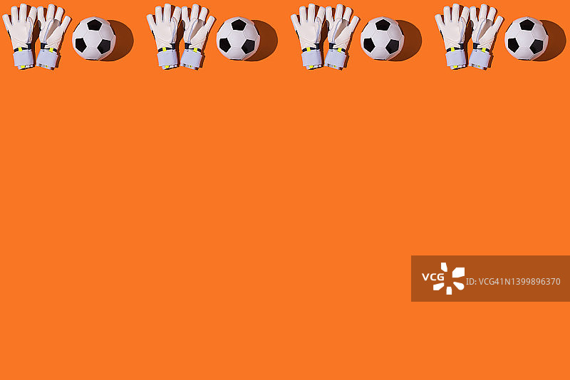 橙色背景上的白色守门员足球手套，足球、体育、比赛和世界冠军概念图片素材