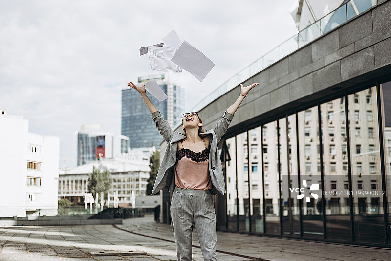在市中心扔纸的年轻快乐的女人图片素材