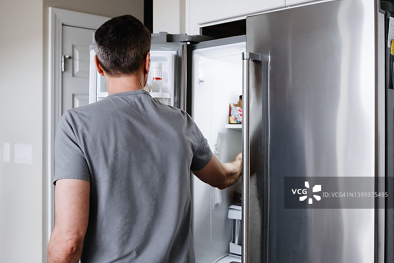 男人伸手进冰箱图片素材