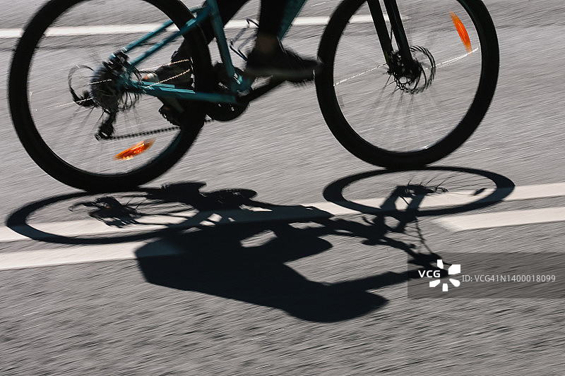 抽象运动背景：沥青路面上黑暗的自行车手轮廓图片素材