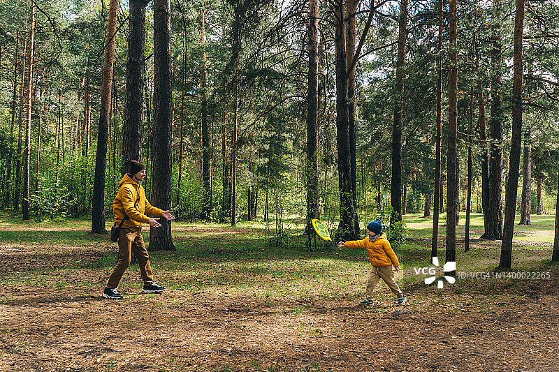 父子在森林里玩耍，阳光明媚，黄绿色调图片素材