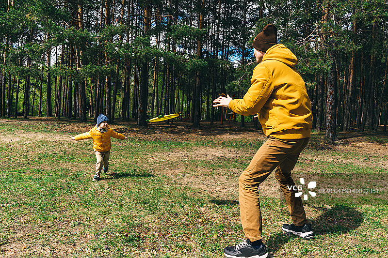 父子在森林里玩耍，阳光明媚，黄绿色调图片素材