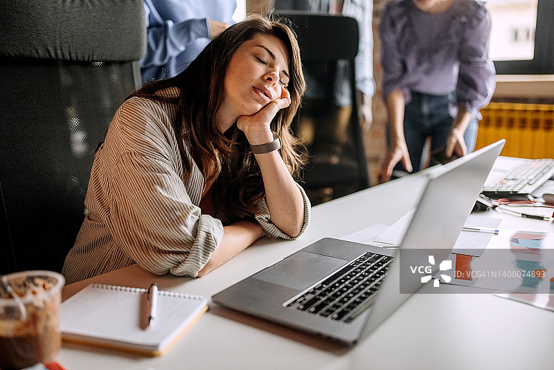 在办公桌上睡觉的疲惫年轻女商人图片素材