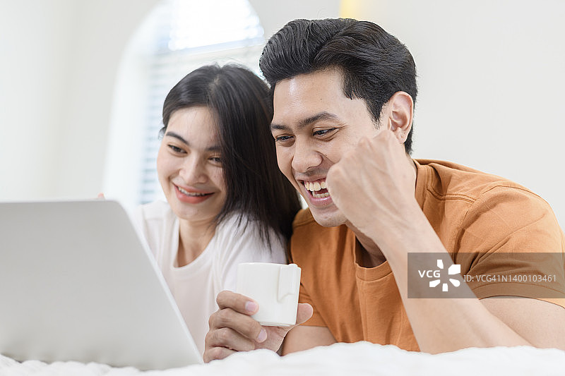 快乐情侣在家使用笔记本电脑图片素材