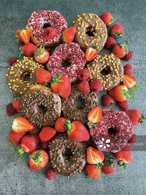 巧克力草莓甜甜圈：淋有巧克力或草莓软糖糖衣和糖屑图片素材