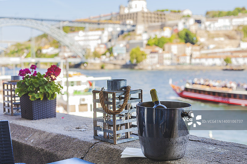杜罗河畔餐厅香槟酒窖中的波特酒，背景是路易斯一世大桥和游船图片素材