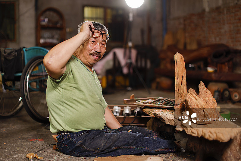 微笑的残疾高级木雕师的肖像图片素材